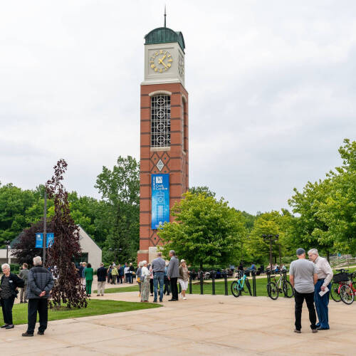 people milling around the base of the Cook Carillon Tower, in center of photo on sidewalks of GVSU's Allendale Campus
